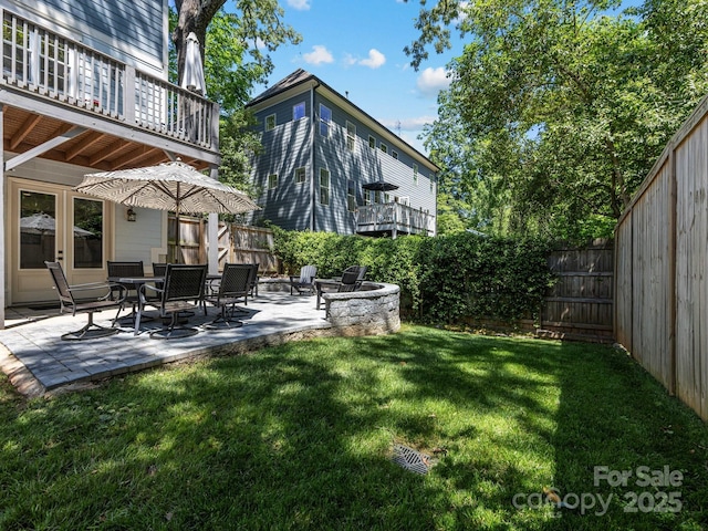 view of yard featuring a patio, a fire pit, a balcony, and a fenced backyard