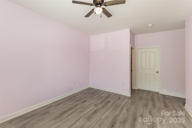 empty room featuring wood finished floors, ceiling fan, baseboards, and a smoke detector