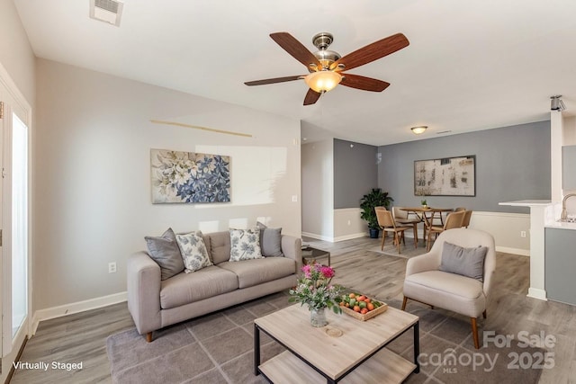 living room featuring wood finished floors, ceiling fan, and baseboards