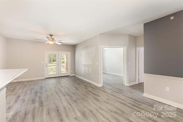 unfurnished living room with a ceiling fan, light wood-type flooring, and baseboards