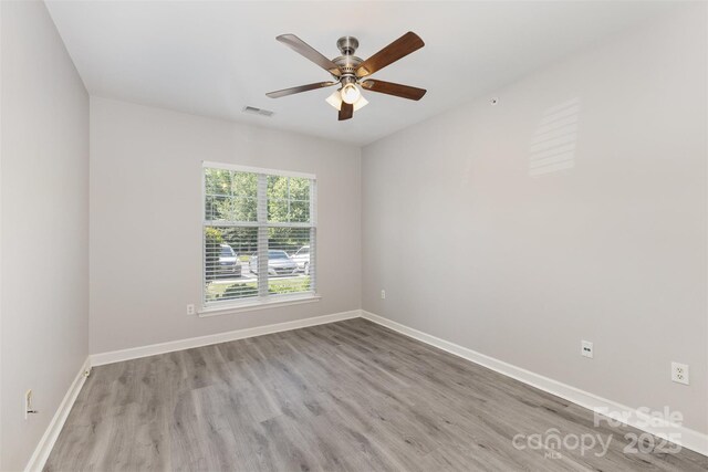 empty room with wood finished floors, baseboards, and ceiling fan