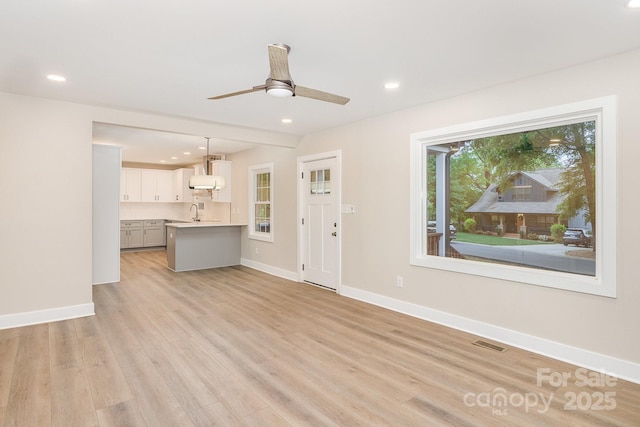 1208 Fordham Rd, Charlotte, NC 28208 - unfurnished living room with baseboards, recessed lighting, light wood-style floors, a ceiling fan, and a sink