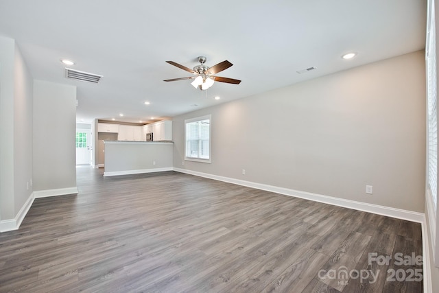 unfurnished living room featuring a wealth of natural light, a ceiling fan, wood finished floors, and visible vents