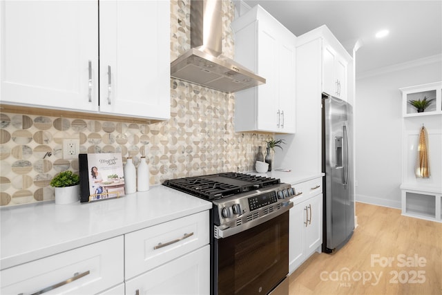 kitchen featuring crown molding, light countertops, wall chimney exhaust hood, and appliances with stainless steel finishes