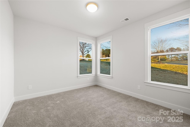 carpeted empty room featuring baseboards, a wealth of natural light, and visible vents