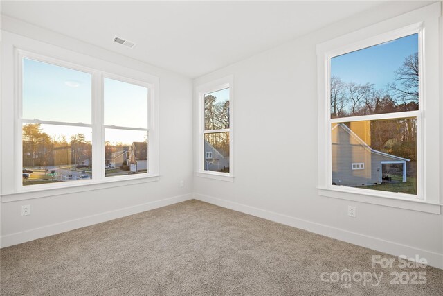 spare room with carpet flooring, baseboards, and visible vents