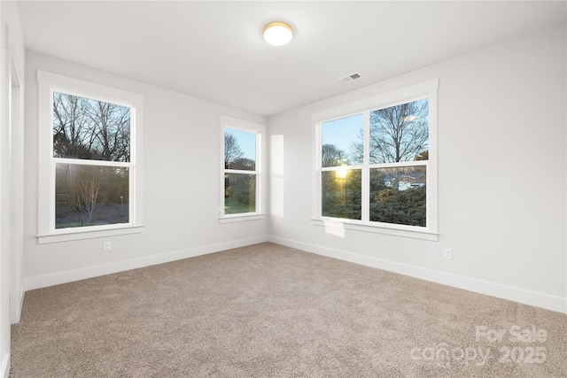 spare room featuring baseboards, visible vents, a healthy amount of sunlight, and carpet