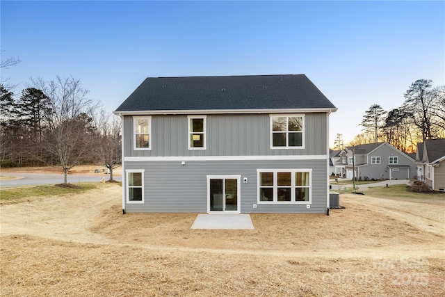 back of house with a patio, central AC unit, and roof with shingles