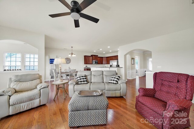 living room with recessed lighting, arched walkways, ceiling fan with notable chandelier, and wood finished floors