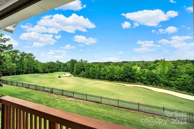 view of community with a lawn, a forest view, fence, and golf course view