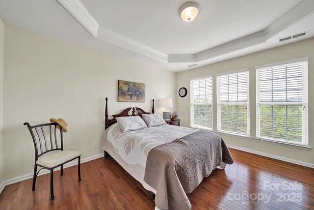 bedroom featuring visible vents, crown molding, wood finished floors, and a tray ceiling
