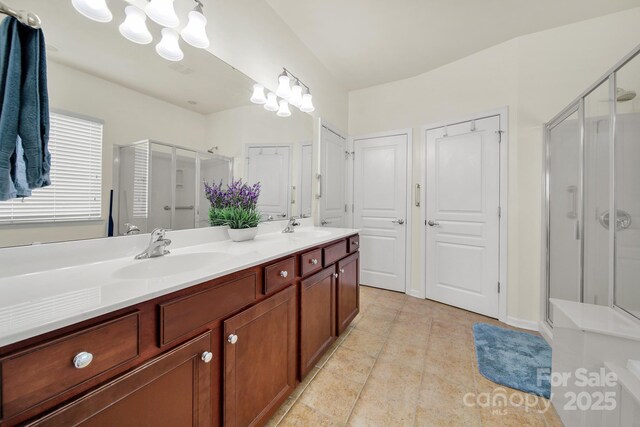full bath featuring a sink, a shower stall, and double vanity