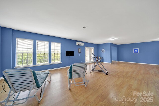 exercise room featuring baseboards, wood finished floors, and a wall mounted air conditioner