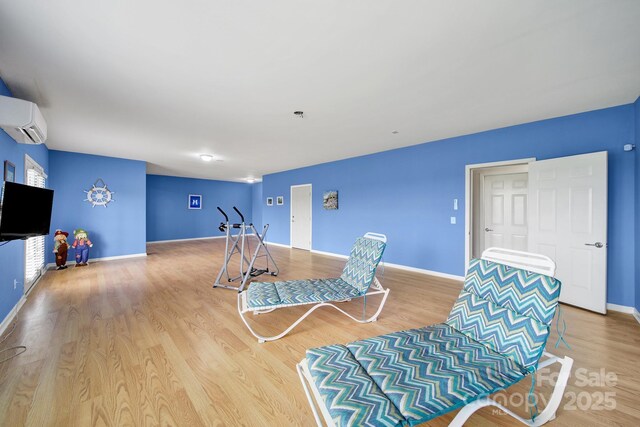 exercise area with baseboards, a wall mounted AC, and wood finished floors