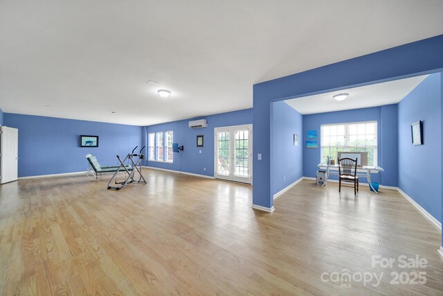 workout area with baseboards, a wall mounted AC, and wood finished floors