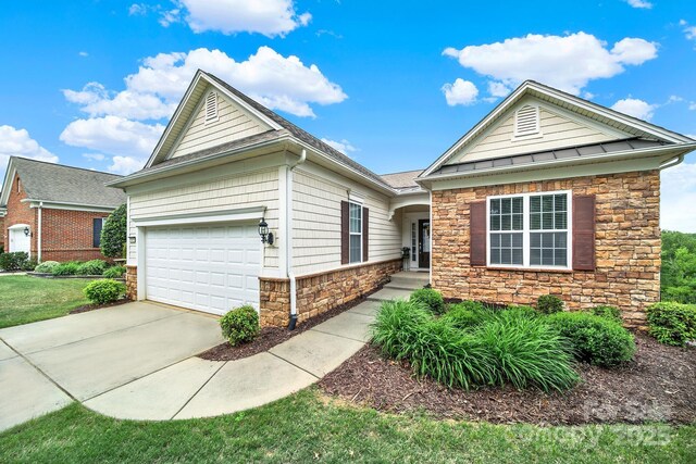 ranch-style home featuring a standing seam roof, driveway, stone siding, and a garage