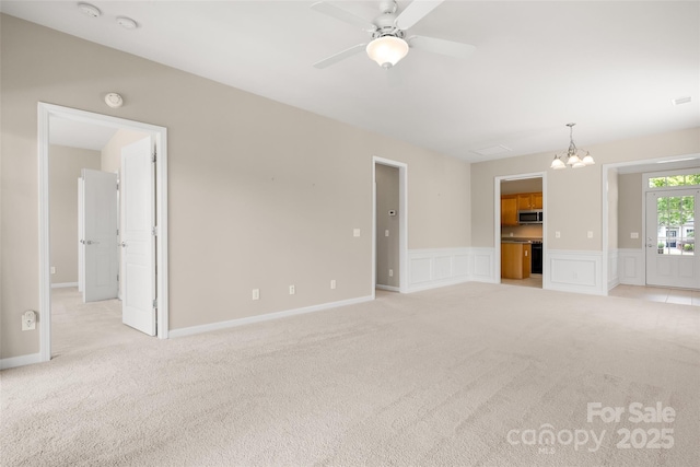 16291 Raven Crest Dr, Indian Land, SC 29707 - unfurnished living room featuring a decorative wall, light colored carpet, ceiling fan with notable chandelier, and a wainscoted wall