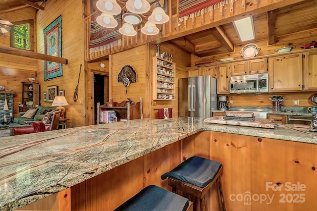 41 Log Cabin Dr, Maggie Valley, NC 28751 - kitchen with wood walls, a breakfast bar, beamed ceiling, wooden ceiling, and stainless steel appliances
