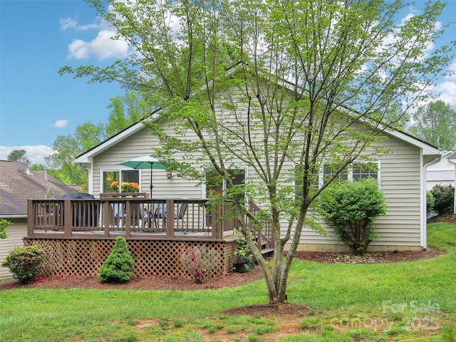 rear view of house featuring a lawn and a deck