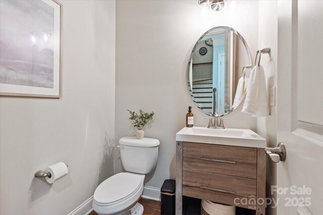 bathroom featuring toilet, baseboards, and vanity