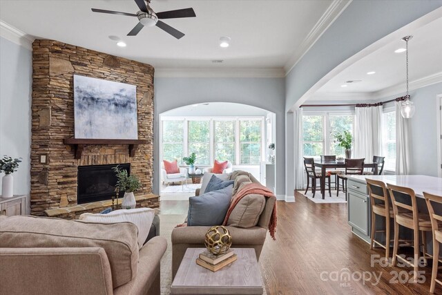 living area with crown molding, a fireplace, ceiling fan, recessed lighting, and dark wood finished floors