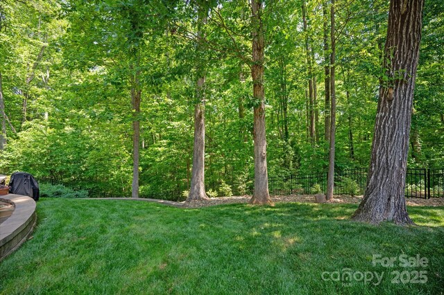 view of yard with fence and a wooded view