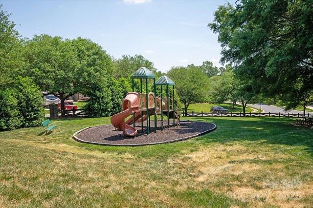 community jungle gym featuring a lawn and fence
