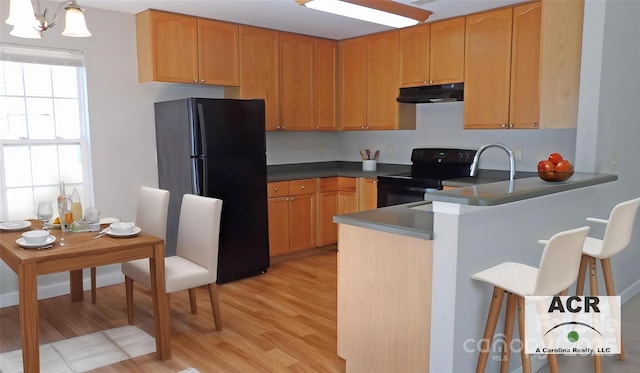 1367 Springview Ct, Rock Hill, SC 29732 - kitchen featuring black appliances, under cabinet range hood, light wood-style flooring, a breakfast bar area, and dark countertops
