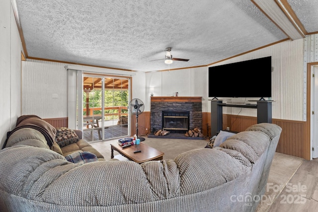 living room with ornamental molding, a ceiling fan, wood walls, and wood finished floors