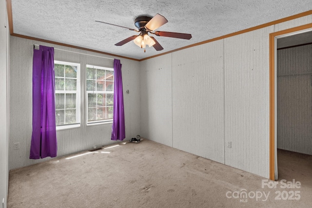 unfurnished bedroom with a textured ceiling, ornamental molding, and carpet