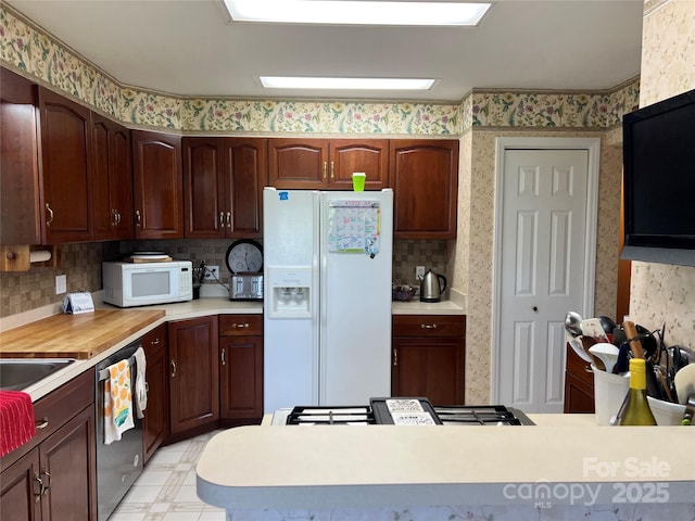 kitchen with white appliances, light countertops, a peninsula, wallpapered walls, and tasteful backsplash