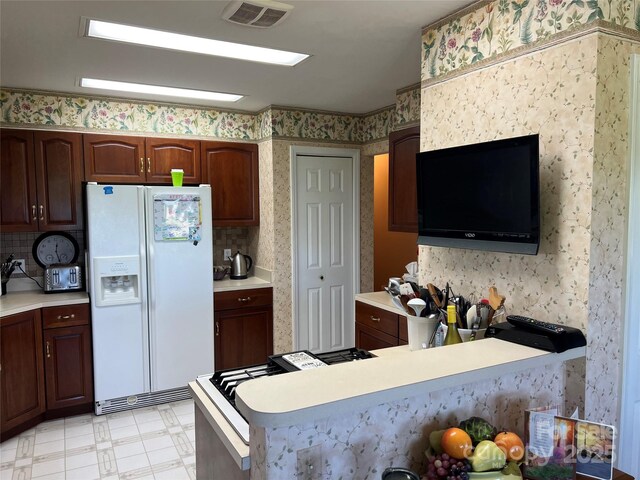 kitchen featuring visible vents, white refrigerator with ice dispenser, light countertops, a peninsula, and light floors