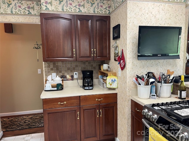 kitchen with light countertops, baseboards, gas stove, and backsplash