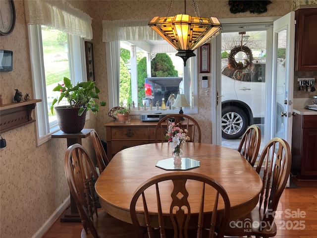 dining area with light wood-style floors, wallpapered walls, and a healthy amount of sunlight