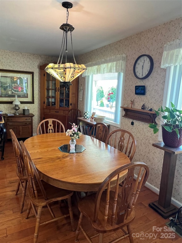 dining room featuring wood-type flooring and wallpapered walls