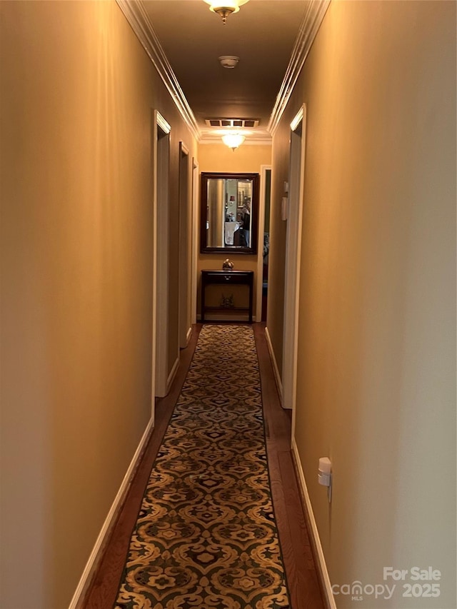 hall with crown molding, baseboards, and visible vents