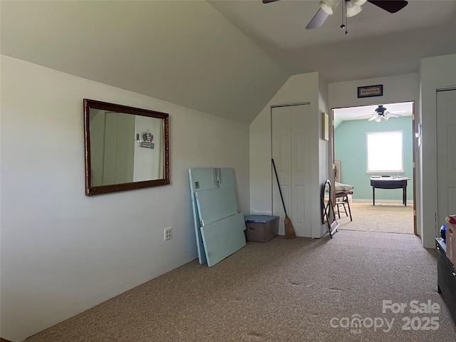 interior space with carpet floors, ceiling fan, freestanding refrigerator, and vaulted ceiling