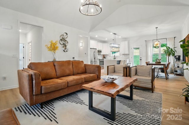 living room featuring recessed lighting, vaulted ceiling, light wood-type flooring, and a chandelier