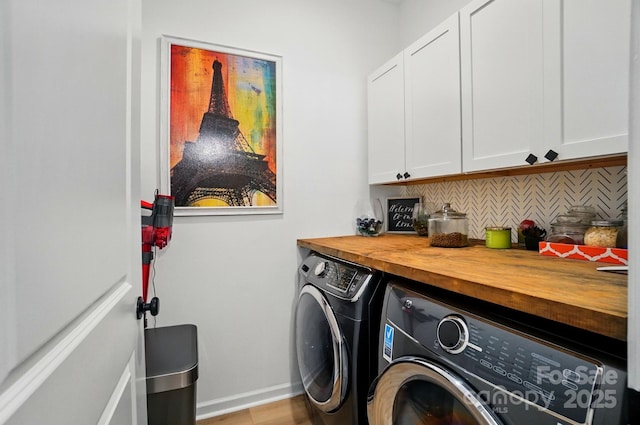 clothes washing area featuring cabinet space, baseboards, light wood finished floors, and washer and dryer
