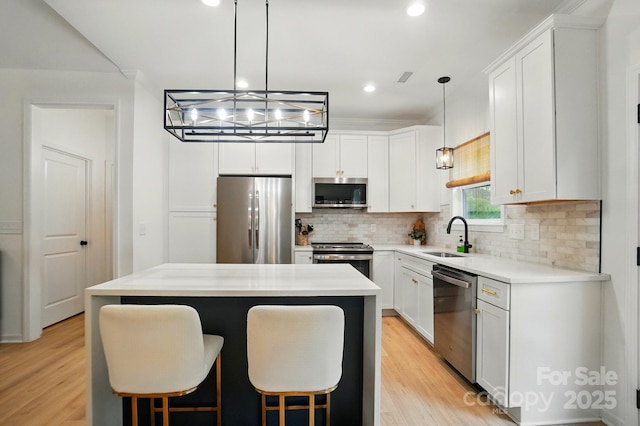 kitchen featuring a sink, light wood finished floors, appliances with stainless steel finishes, and backsplash