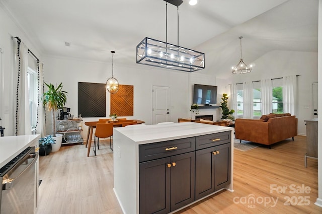 kitchen with stainless steel dishwasher, hanging light fixtures, light wood-style flooring, and light countertops