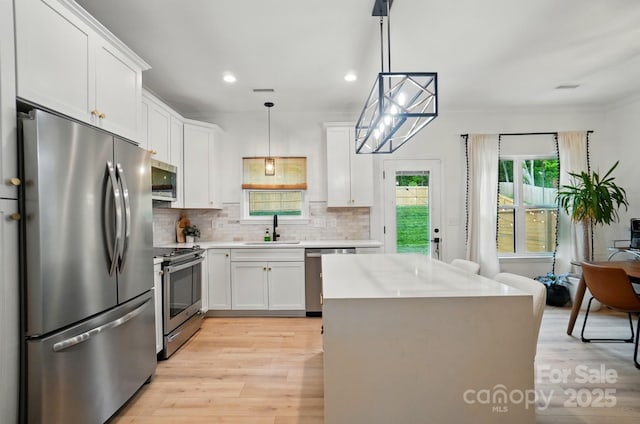 kitchen with light countertops, a sink, light wood-style floors, and stainless steel appliances