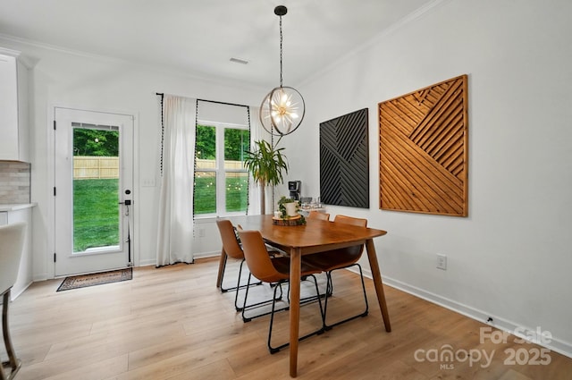 dining room featuring crown molding, baseboards, light wood finished floors, and a notable chandelier