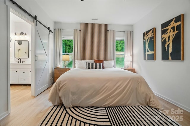 bedroom featuring a barn door, multiple windows, and light wood-style floors