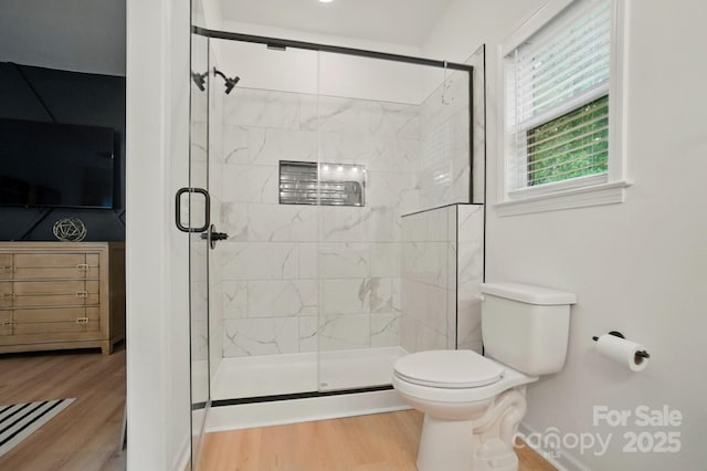 bathroom with a stall shower, wood finished floors, and toilet