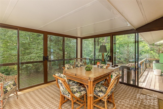 sunroom with plenty of natural light, expansive windows, and a deck