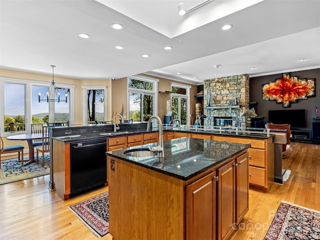 kitchen with a sink, light wood finished floors, a spacious island, and dishwasher