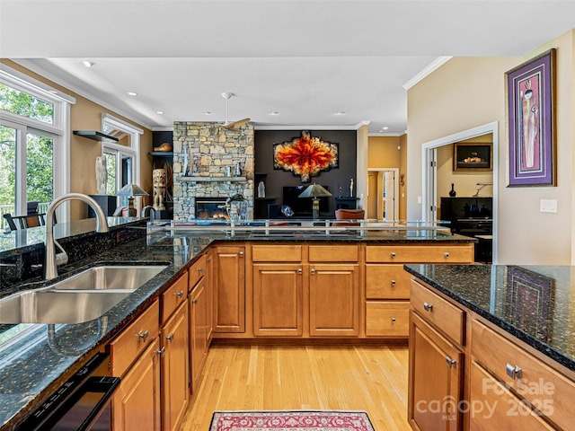 kitchen featuring crown molding, a sink, a fireplace, light wood-style floors, and brown cabinetry