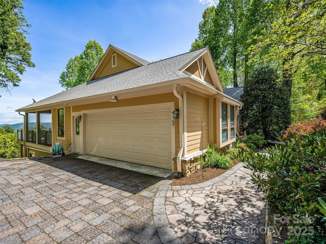 view of side of property featuring a garage, roof with shingles, and aphalt driveway