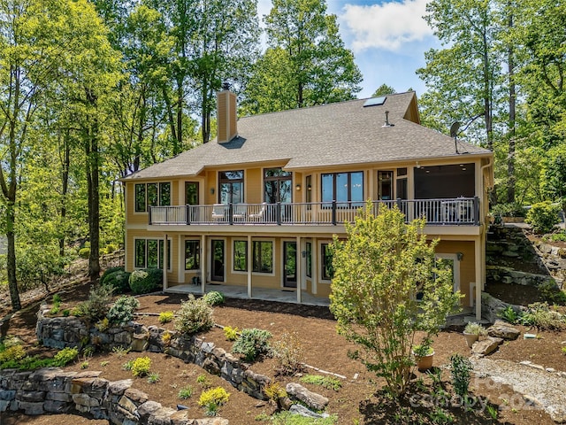 rear view of house with a shingled roof, a patio area, french doors, and a chimney